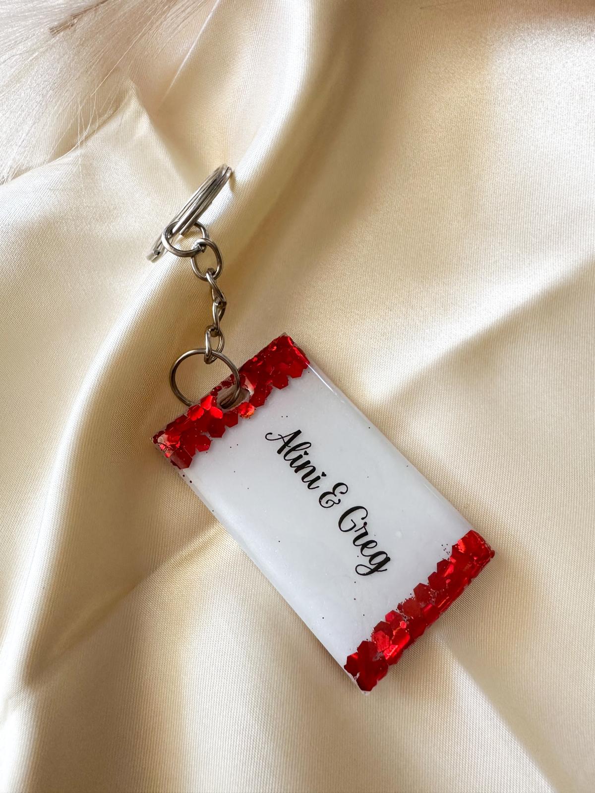 Back of personalised resin keychain with couple names Alini and Greg in elegant script