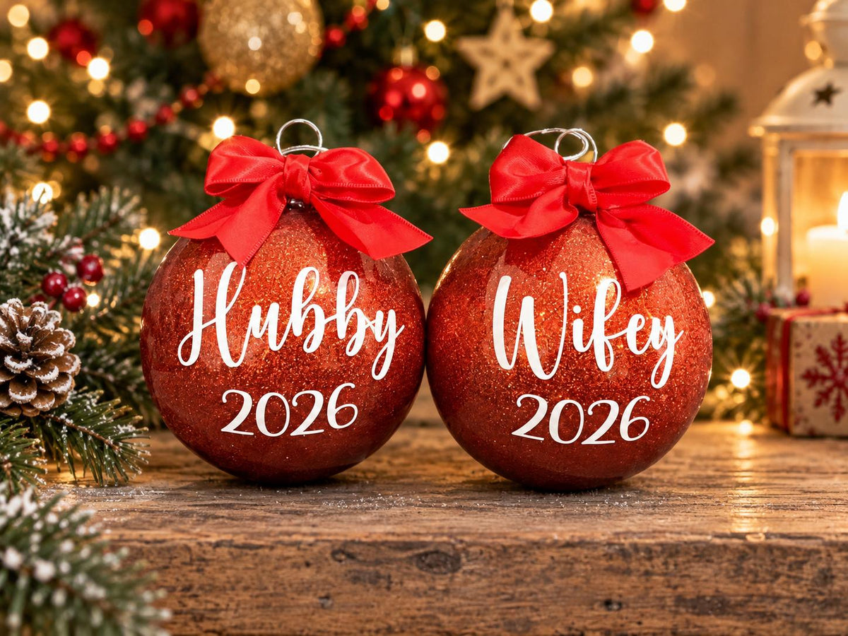 Two red glitter personalised name Christmas baubles reading Hubby 2026 and Wifey 2026 with red ribbon bows